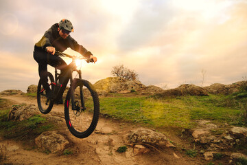 Fototapeta na wymiar Professional Cyclist Riding Bike on the Autumn Rocky Trail at Sunset. Extreme Sport and Enduro Biking Concept.