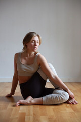 Obraz premium Full length of a fit young woman doing the half spinal twist pose on wooden floor