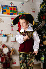 Obraz premium Little boy child dressed as pirate for Halloween on background of Christmas tree. Kid in carnival costumes for Christmas