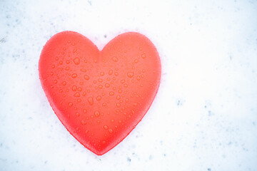 red heart with water drops on the snow