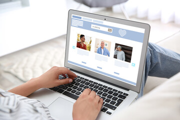 Young woman visiting online dating site via laptop indoors, closeup