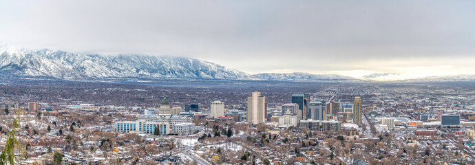 Panorama of Salt Lake City with snowy mountain and gray cloudy sky in winter