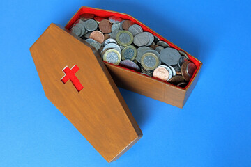 Sterling coins in a scale model coffin. The costs of being buried and funerals concept.