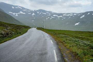 Pass road with snow fields on the side in the mountains of Norway