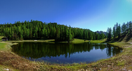Fototapeta na wymiar blue sky trees and mountains with a reflection in a lake panorama