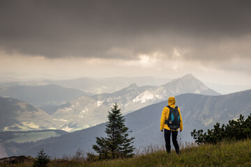 Hiker looking at cloudy sky over mountain range. Woman hiking in nature during bad weather. View at mountain peak know as Velky Rozsutec in natural parkland Mala Fatra, Slovakia