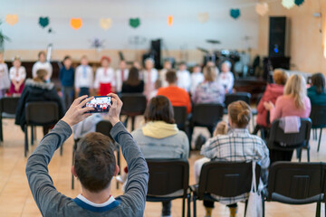Parents at the performance of children in kindergarten or school. Children on stage. Many parents are watching the kids performance in the hall during Chistmas holiday, blur. toned
