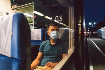 Sad man wears protective mask in train to protect the respiratory system from coronavirus infection, covid-19. Preventive measure. New normal. Travel safely on railway public transport