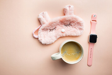 sleeping mask and coffee cup on pink background. The concept of starting a new day, good morning or ending the day, late evening.