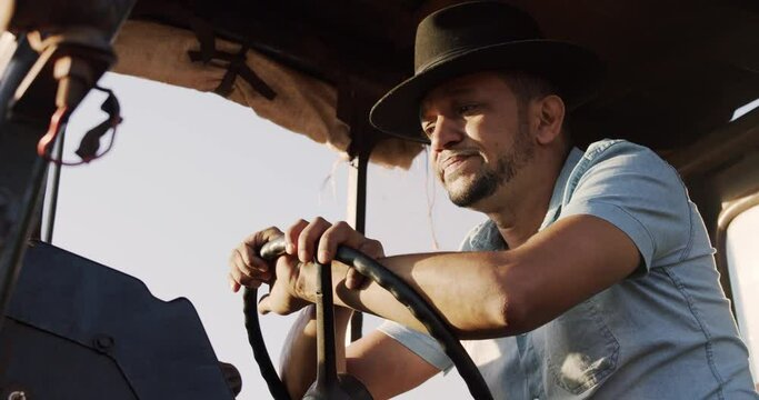 Young Latin American farmer inside the tractor, thoughtful, worried or tired. 4K.