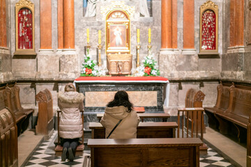 A woman in a temple prays to God. Woman praying in front of altar. Praying woman in front of altar....