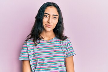 Hispanic teenager girl with dental braces wearing casual clothes relaxed with serious expression on...