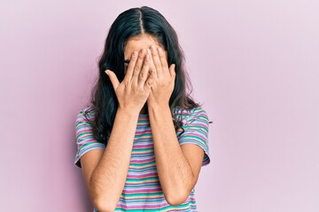 Hispanic teenager girl with dental braces wearing casual clothes with sad expression covering face with hands while crying. depression concept.