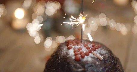 Bengal fire burning on a chocolate pie with a Christmas tree made of berries, close-up slow motion shot