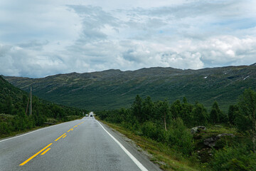 Street through a landscape with mountains in Norway