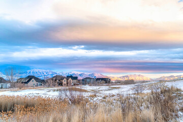 Sunset view of snowy valley in winter with homes against sunlit frosted mountain