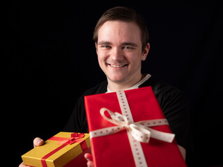 young guy in black t-shirt suit stretches out his hand with gifts