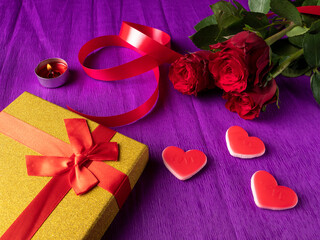 Yellow gift next to hearts and ribbon and red roses