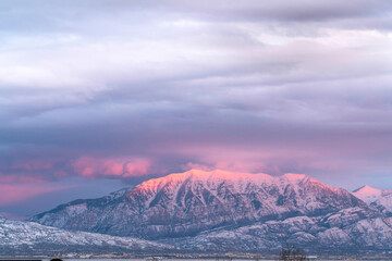 Fototapeta na wymiar Foggy landscape of majestic snowy mountain in winter with sunlit peak at sunset
