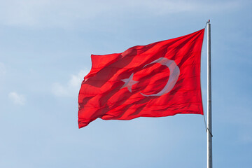 Turkish flag waving in blue sky.