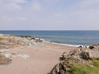 The Cove beach in Greystones, Co. Wicklow, Ireland. Seascape with the Irish Sea, sandy beach and rocks on the sides. Sunny summer day.