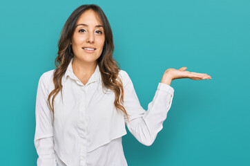 Young brunette woman wearing casual clothes smiling cheerful presenting and pointing with palm of hand looking at the camera.