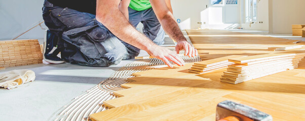 worker installing oak herringbone parquet floor during home improvement - 402882919