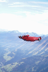 Wingsuit flier glides over snowcapped mountains