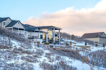 Fototapeta na wymiar Beautiful homes on mountain neighborhood with snowy slope against cloudy sky