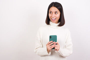 Copyspace photo of Young brunette woman wearing white knitted sweater against white background stupor with something occurring in social media