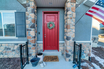 Fototapeta na wymiar Red front door with wreath and portico with stone columns at the home entrance