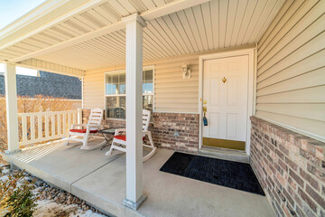 Open front porch with rocking chairs against white siding and stone brick wall