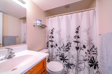 Interior of small bathroom with printed curtain on the bathtub and shower area