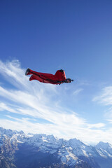 Wingsuit flier glides over snowcapped mountains