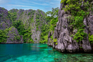 Blue crystal water in paradise Bay with boats on the wooden pier at Kayangan Lake in Coron island,...