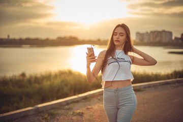 girl listening to music with smartphone walking in the city with headphones smiling - relax, youth, emancipation concept