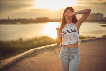 girl listening to music with smartphone walking in the city with headphones smiling - relax, youth, emancipation concept