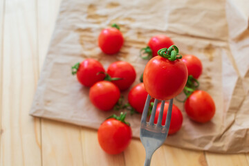 Cherry tomatoes. Tomato on a fork on kraft paper.