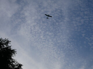 Frothy clouds with a light aircraft flying overhead 