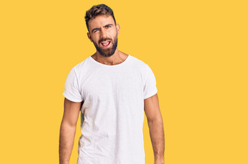 Young hispanic man wearing casual white tshirt winking looking at the camera with sexy expression, cheerful and happy face.
