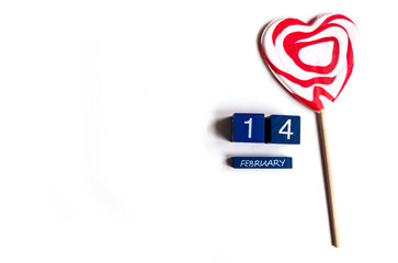 Top view of 14 February lettering and a heart-shaped lollypop on white background, copy space