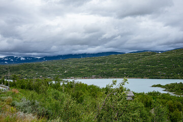 Fototapeta na wymiar Lake with mountains and green land around it