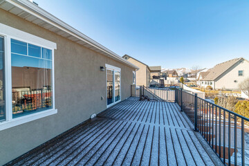 Spacious deck of home with metal railing wooden flooring and stairs to the yard