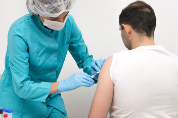 Medical worker vaccinates a middle-aged man in the arm in a medical office.Medicine and healthcare concept.Vaccination against coronavirus.