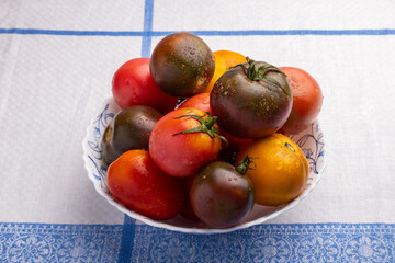 a plate of ripe multicolored tomatoes on a table