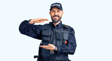 Young handsome man wearing police uniform gesturing with hands showing big and large size sign, measure symbol. smiling looking at the camera. measuring concept.