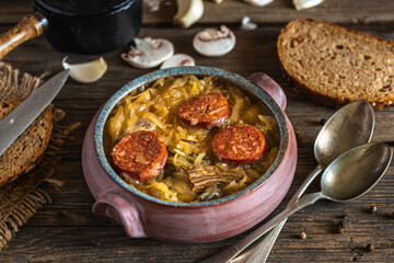 Christmas cabbage soup in ceramic bowl on natural wooden background.