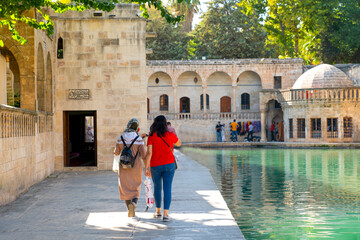 Rear view of two female tourists near Balikli Gol and historic buildings in background, Sanliurfa,...