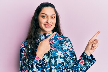 Beautiful middle eastern woman wearing casual floral jacket smiling and looking at the camera pointing with two hands and fingers to the side.