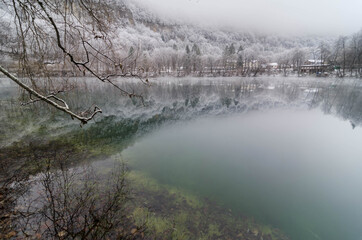 Fabulous view with reflection of trees in a lake with crystal clear blue water. Location Blue Lake, Kabardino-Balkaria. North Caucasus, Russia